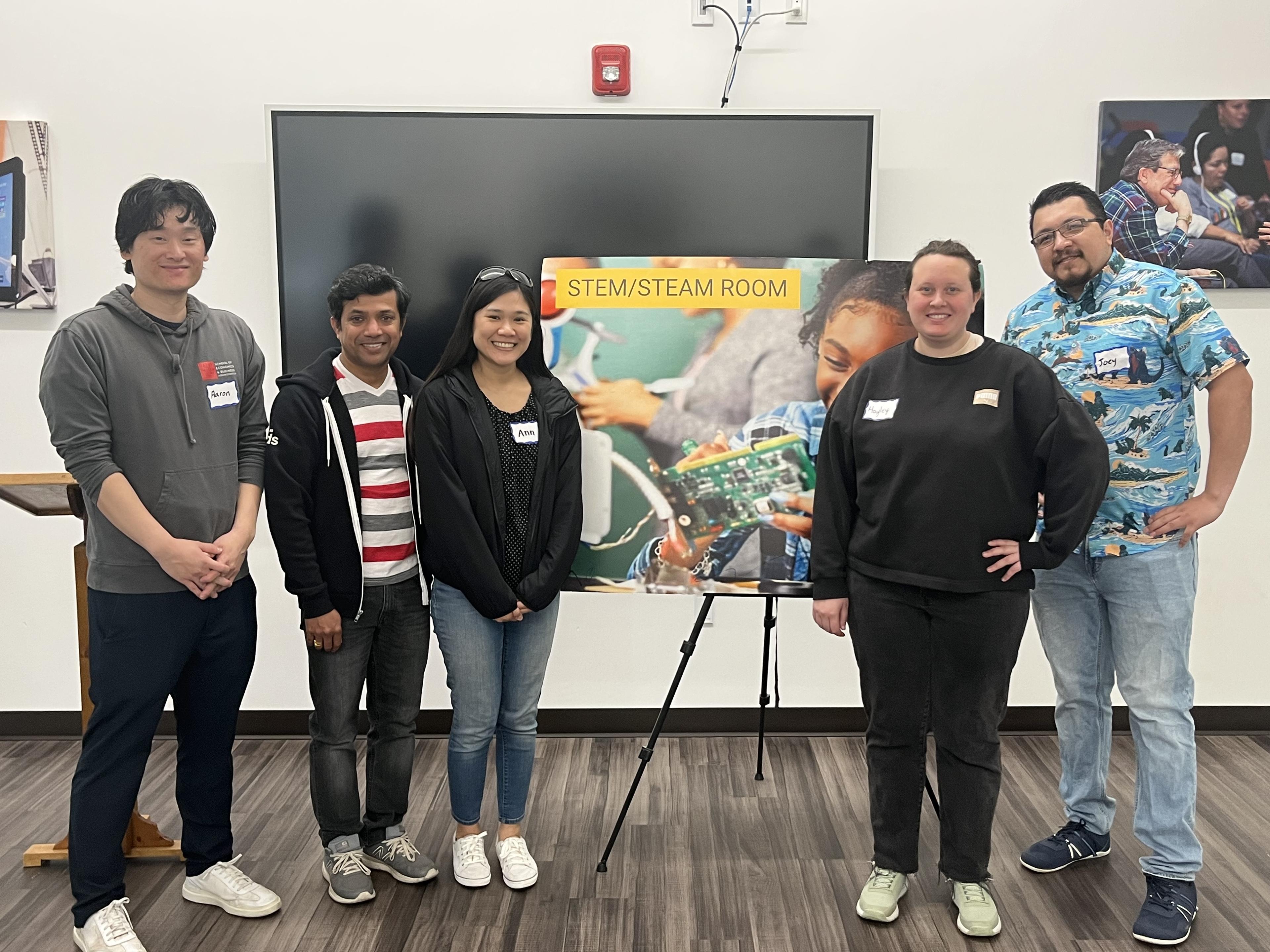 Volunteers standing beside the STEM/STEAM room sign at a Hayward Promise Neighborhoods workshop