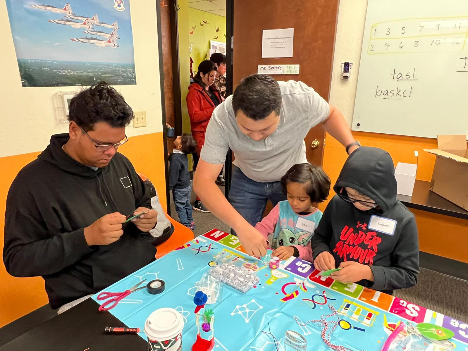 Kids and volunteers building electronics projects at a San Ramon youth workshop